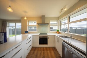 Una cucina moderna con mobili bianchi, un lavello in acciaio inossidabile e un forno a incasso.