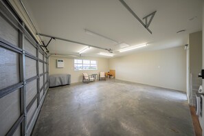 Un garaje espacioso con piso de concreto, un ventanal y una puerta con reja de metal.