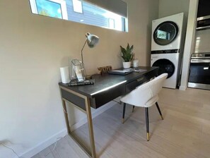 A modern kitchen with a built-in washing machine, a desk with a lamp, and a potted plant. - 1-BR guest house steps from Meteor/downtown square (Bentonville)