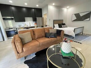 Relax in this stylish living space with a comfortable sofa, coffee table, and modern kitchen area.