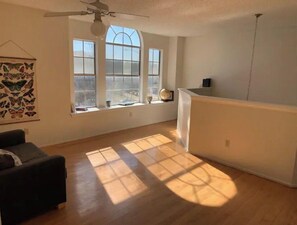 Relax in this serene space with a high ceiling, large window, and comfortable sofa.