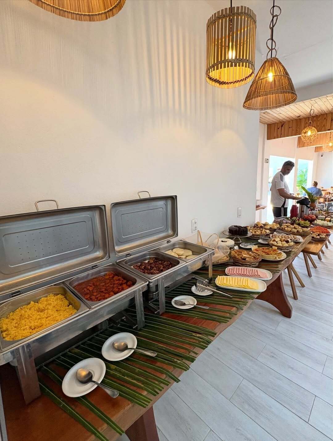 A buffet setup with various food items and a person serving.