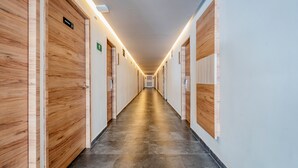 A long, well-lit hallway with wooden doors on both sides, leading to rooms. - Hotel Central Merida by Kavia (Mérida)