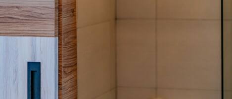 A modern bathroom with a wooden panel design, a toilet with a paper holder, and a glass shower enclosure.