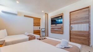 A hotel room with two beds, a TV mounted on the wall, and wooden paneling. - Hotel Central Merida by Kavia (Mérida)