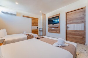 Habitación de hotel con dos camas, un televisor montado en la pared y paneles de madera.