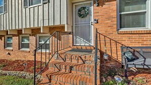 A brick building with a front door, a set of stairs leading to the entrance, and a bench outside.