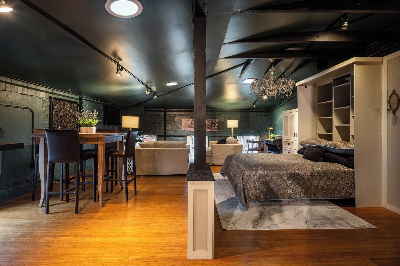 A cozy loft-style bedroom with a large bed, a desk, and a seating area.