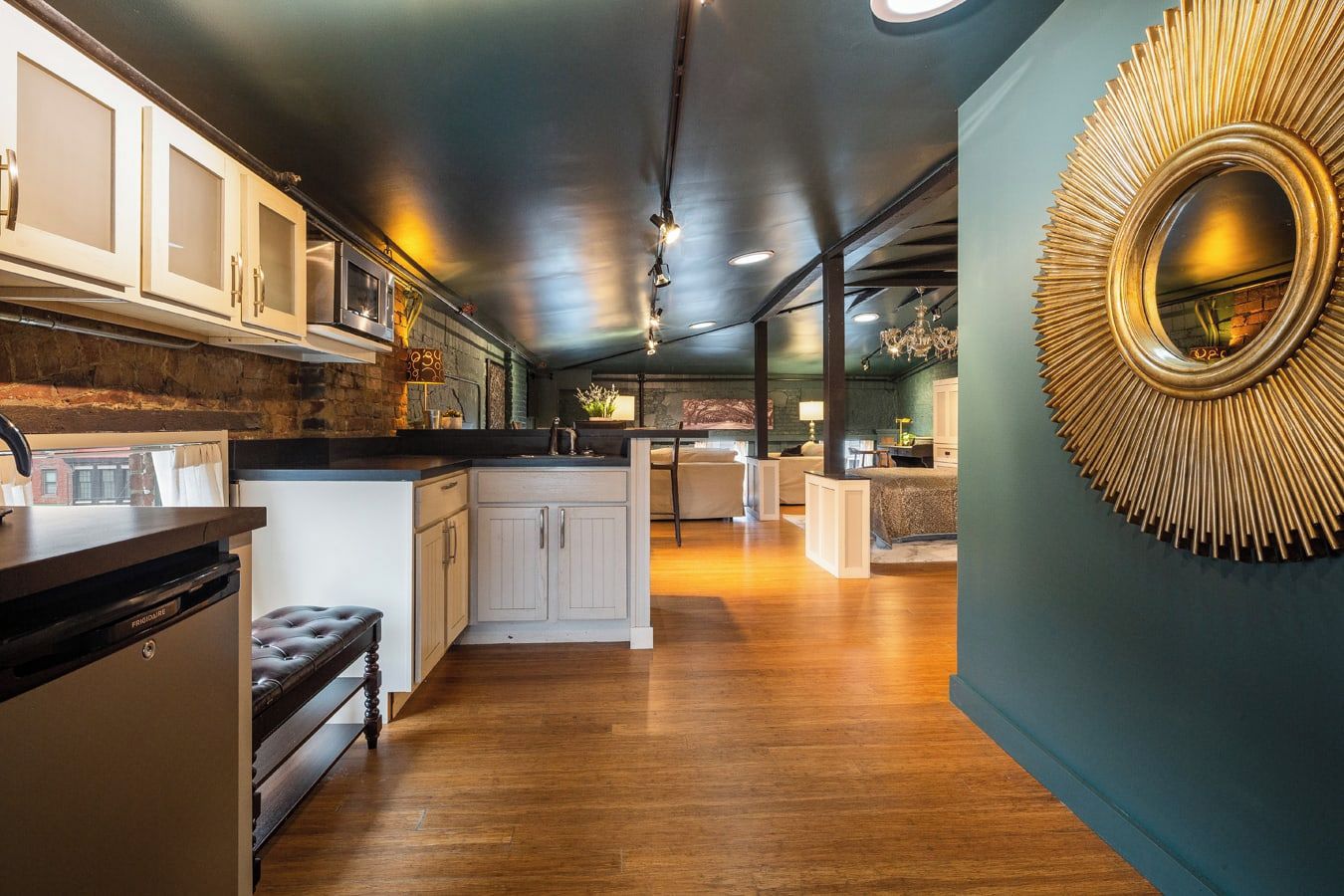 Una cocina moderna con una isla central, armarios blancos y un espejo grande con un marco de diseño radial.