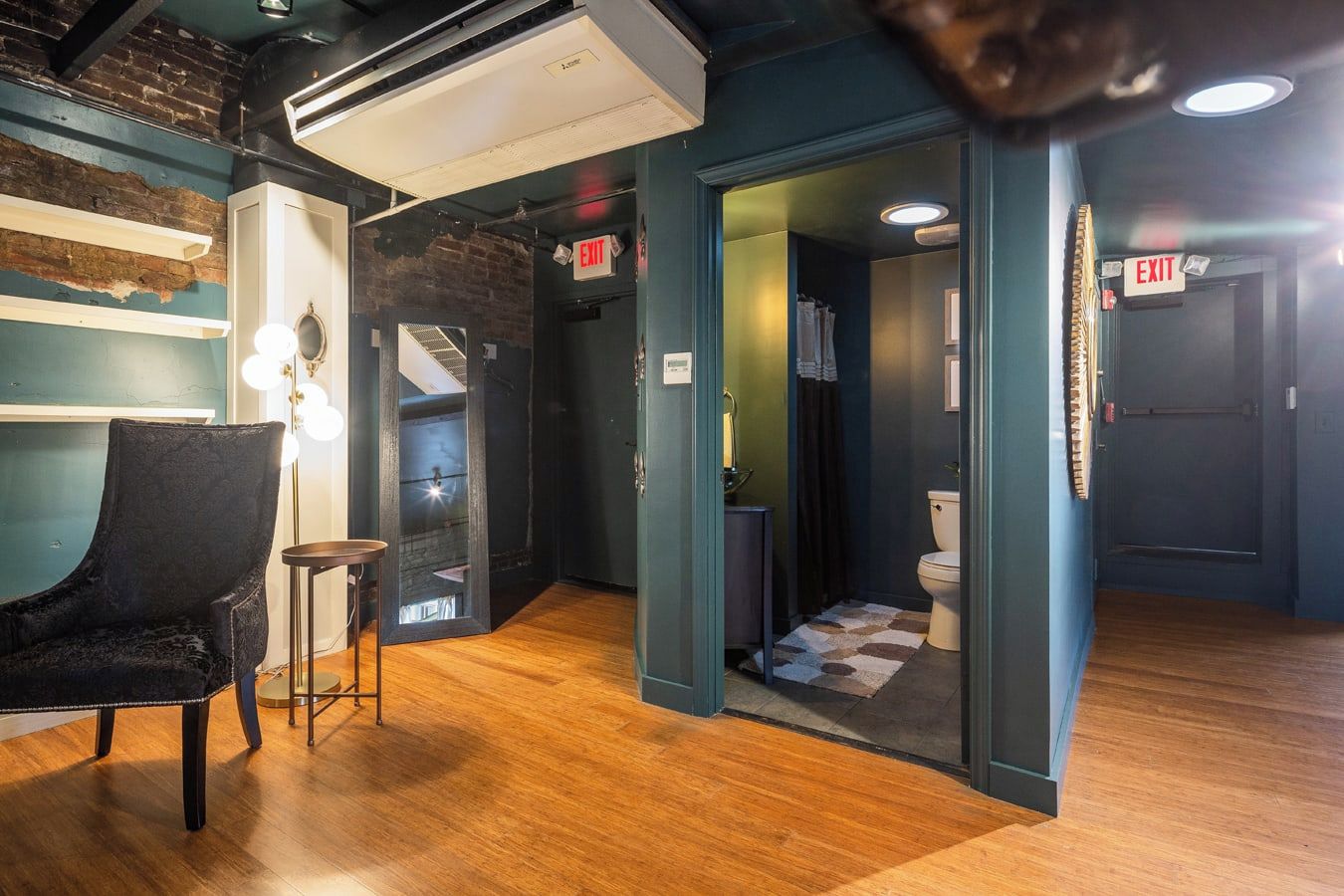 A modern interior with a black leather chair, a small table, and an air conditioning unit.