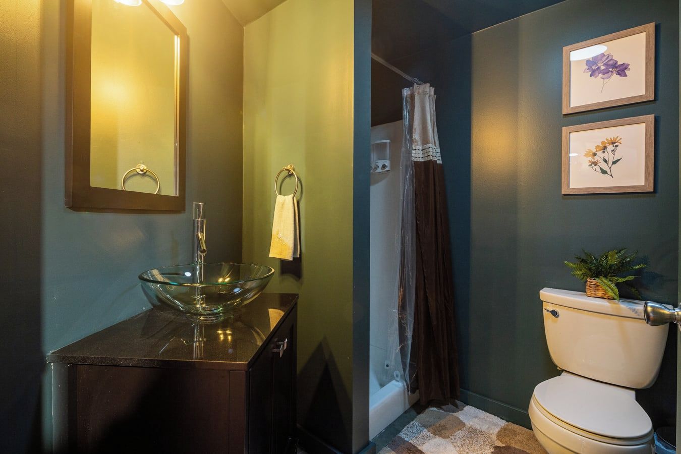 A bathroom with a glass bowl sink, a toilet, and a shower curtain.