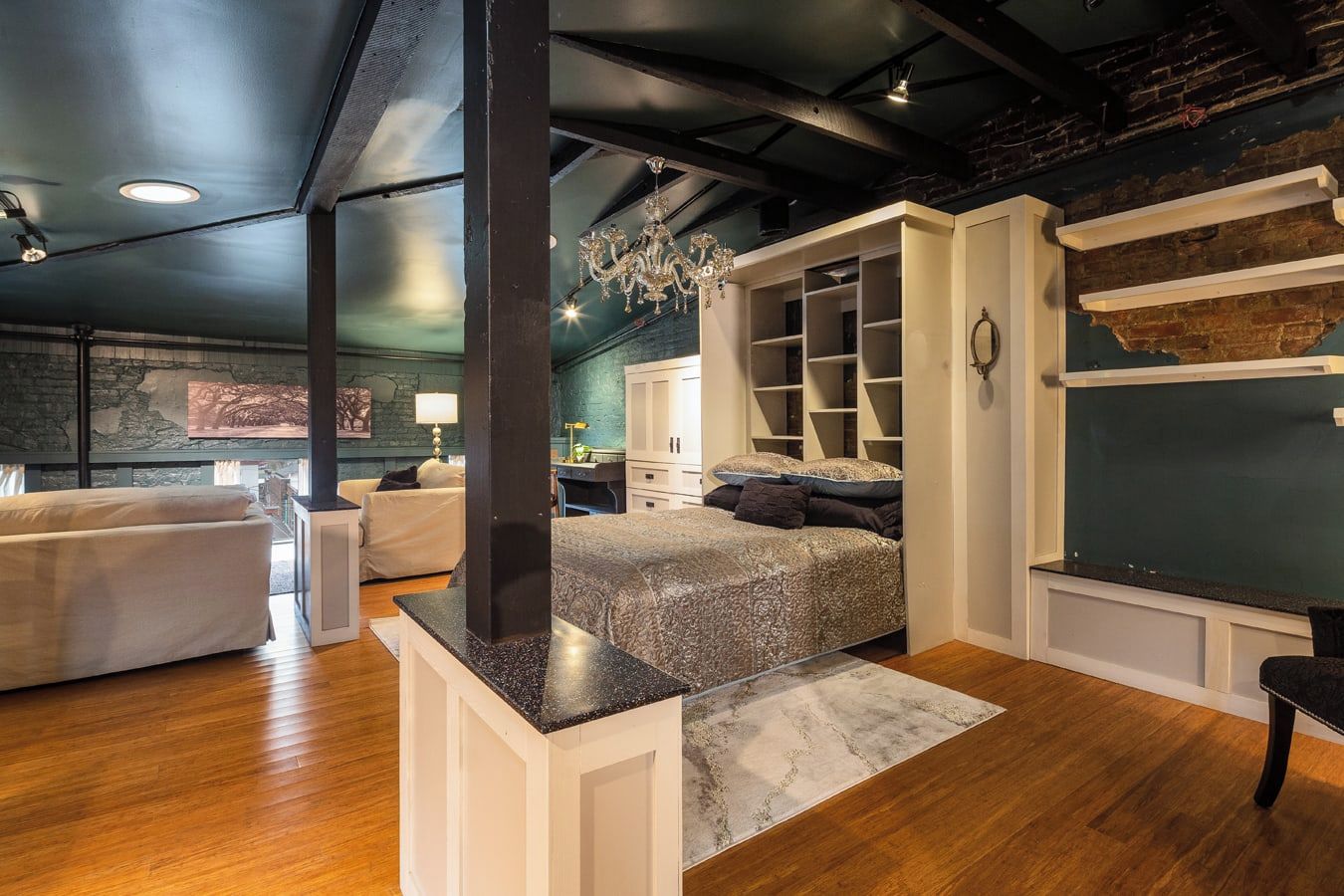 A modern bedroom with a large bed, built-in shelving, and a stone accent wall.