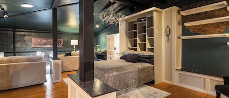 A modern bedroom with a large bed, built-in shelving, and a stone accent wall.