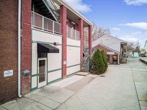 A brick building with a no parking sign, a covered entrance, and a small tree in front.