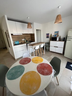 A modern kitchen with white cabinets, a wooden countertop, and a dining area with a round table and chairs.