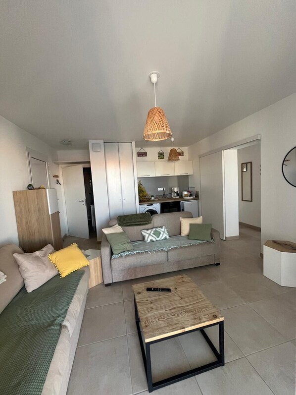 A modern living room with a sofa, coffee table, and kitchen area in the background.