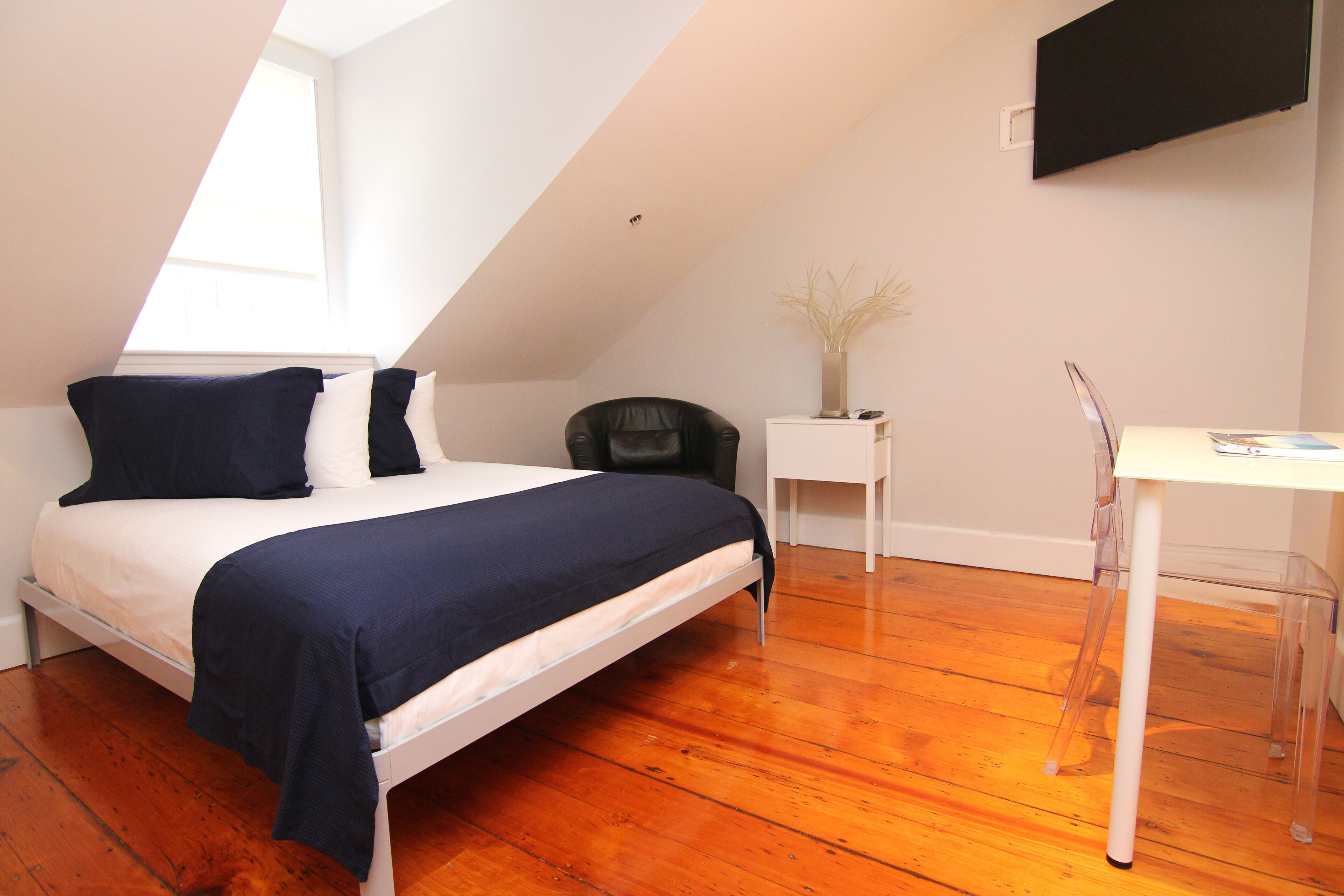A bedroom with a bed, a desk, and a chair.