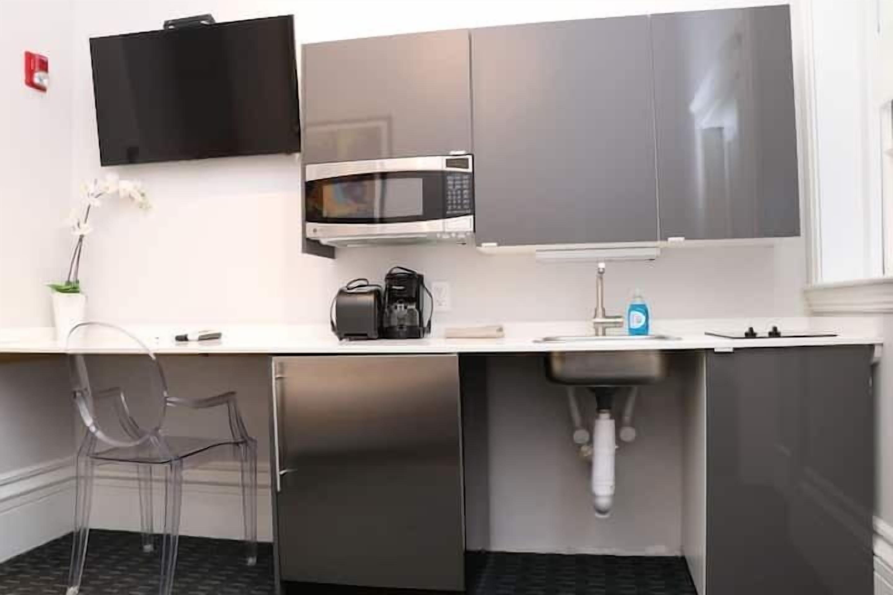 A compact kitchenette with a microwave, coffee maker, and a sink.