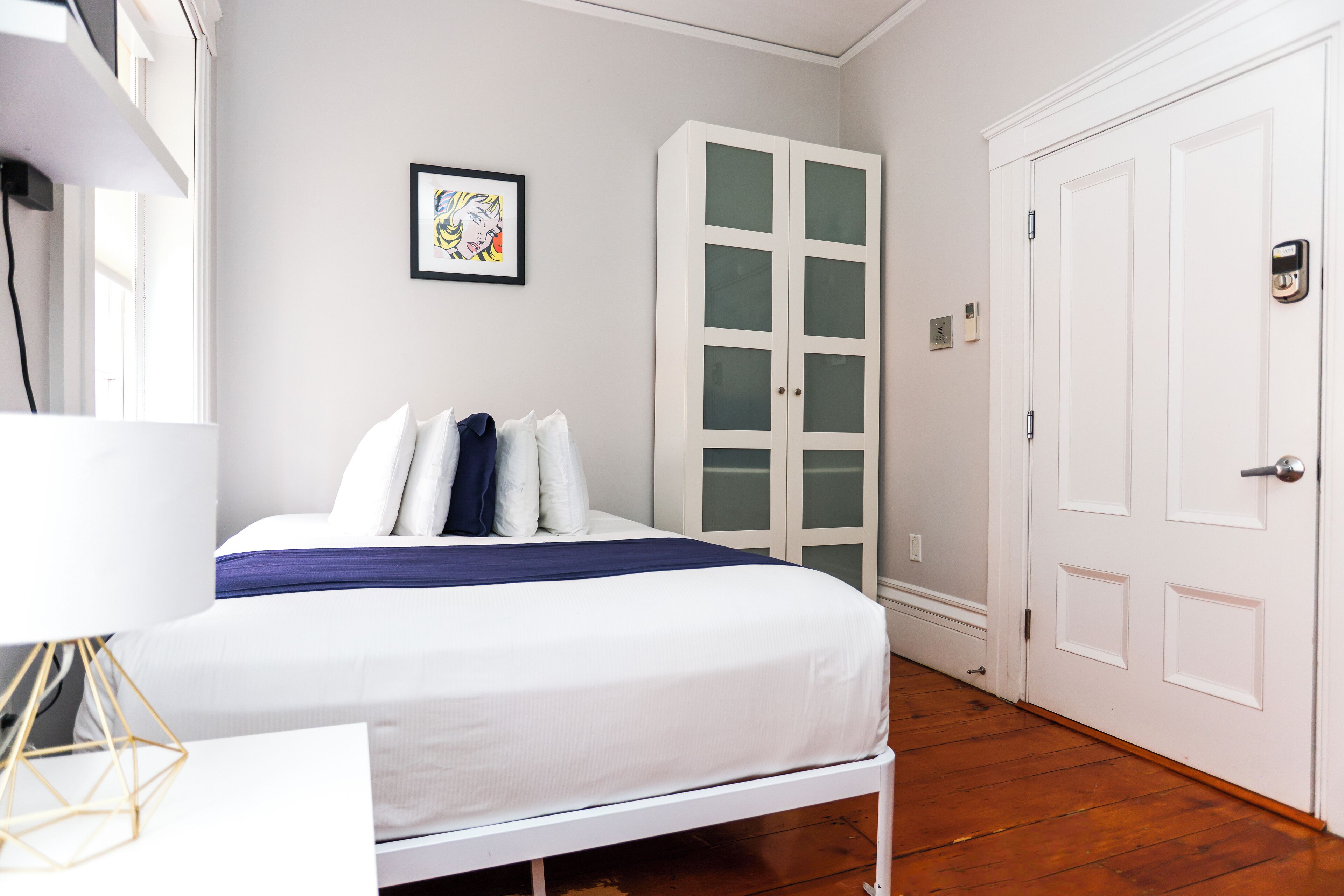A bedroom with a bed, a white wardrobe, and a door.