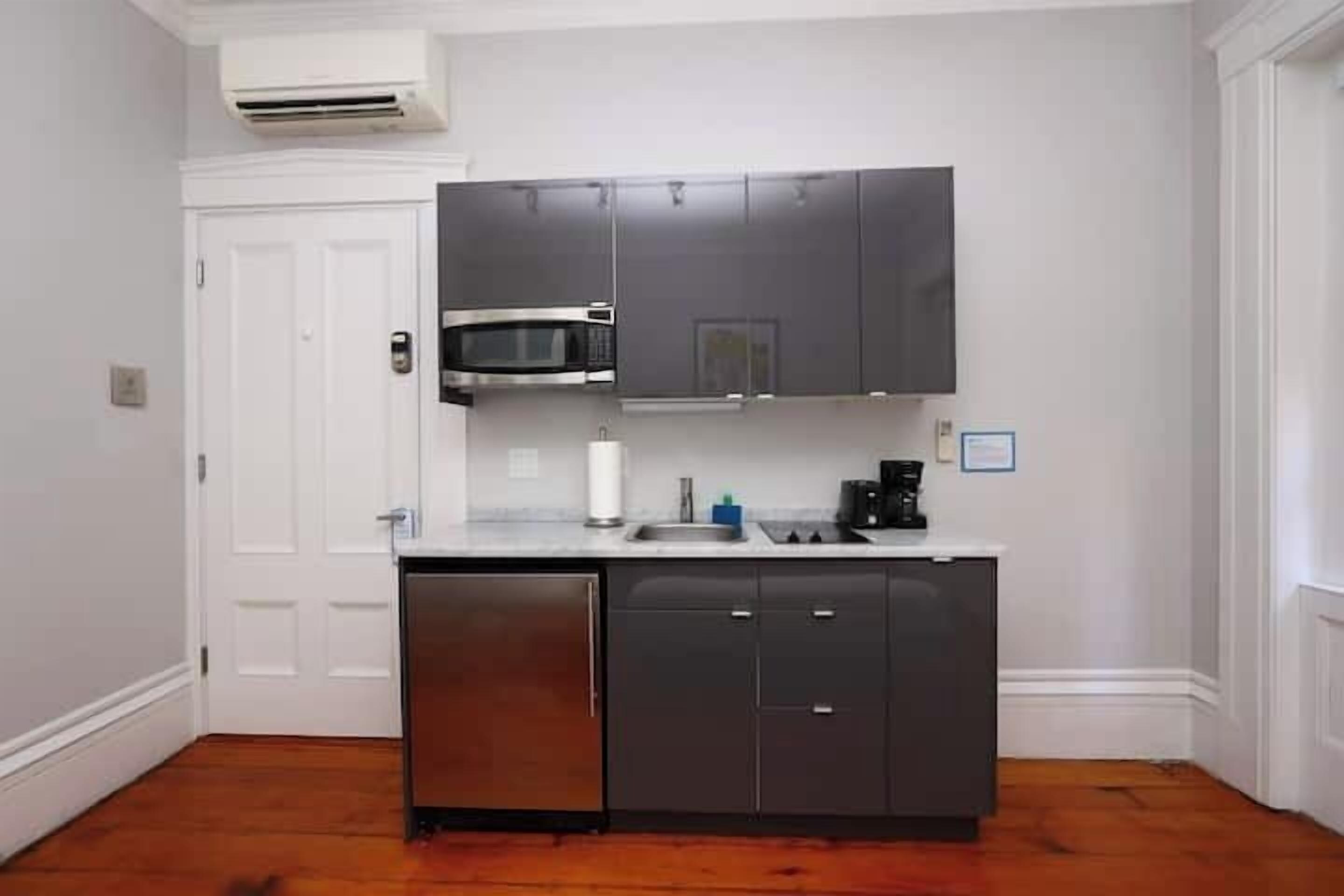 Una cocina compacta con microondas integrado, lavavajillas y muebles oscuros.