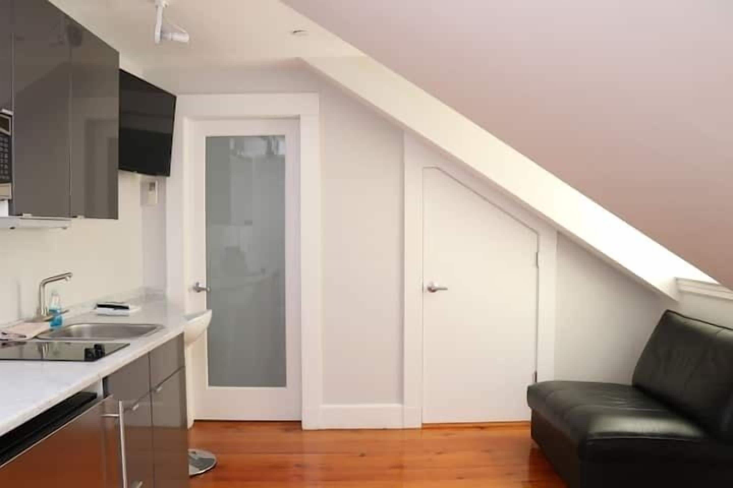 Une cuisine de taille réduite avec un plan de travail blanc, un évier et une chaise en cuir noir.