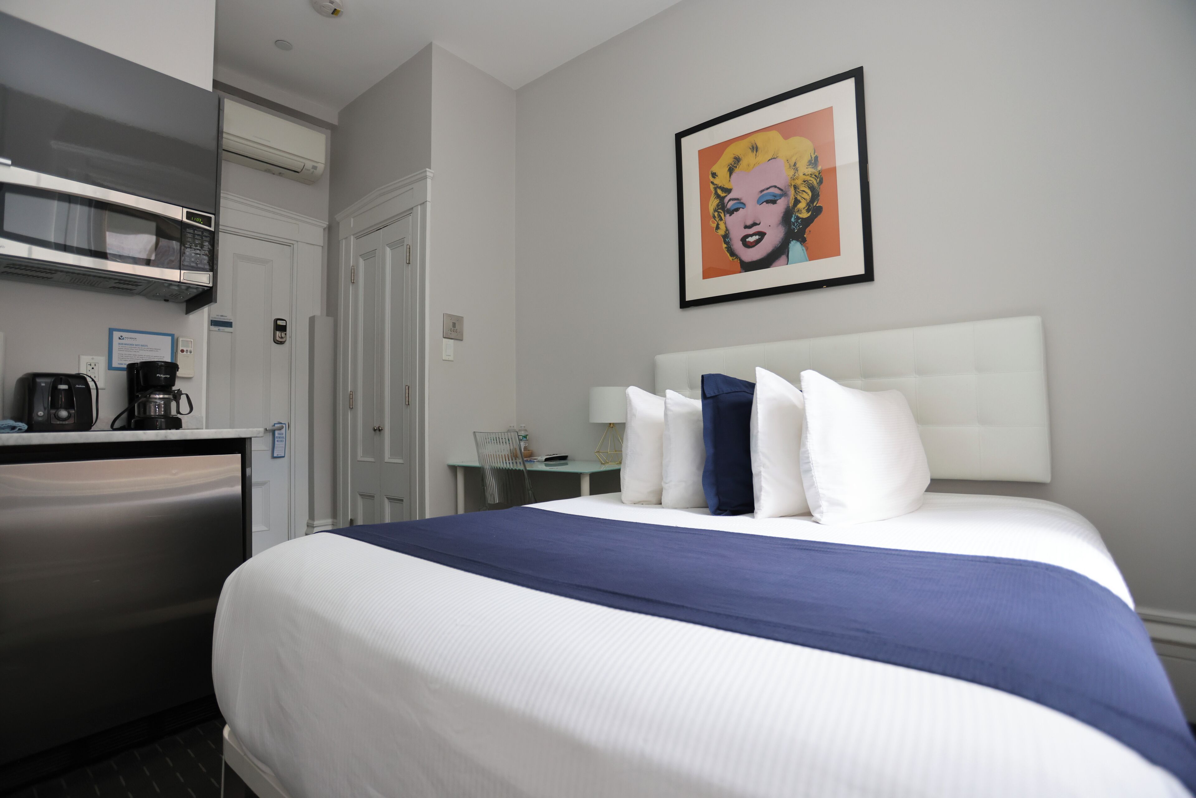Hotelkamer met een bed, een bureau, een magnetron, een koffiezetapparaat en een lijst met een foto aan de muur.