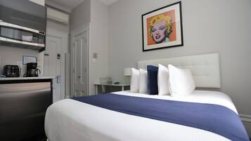 Hotelkamer met een bed, een bureau, een magnetron, een koffiezetapparaat en een lijst met een foto aan de muur.