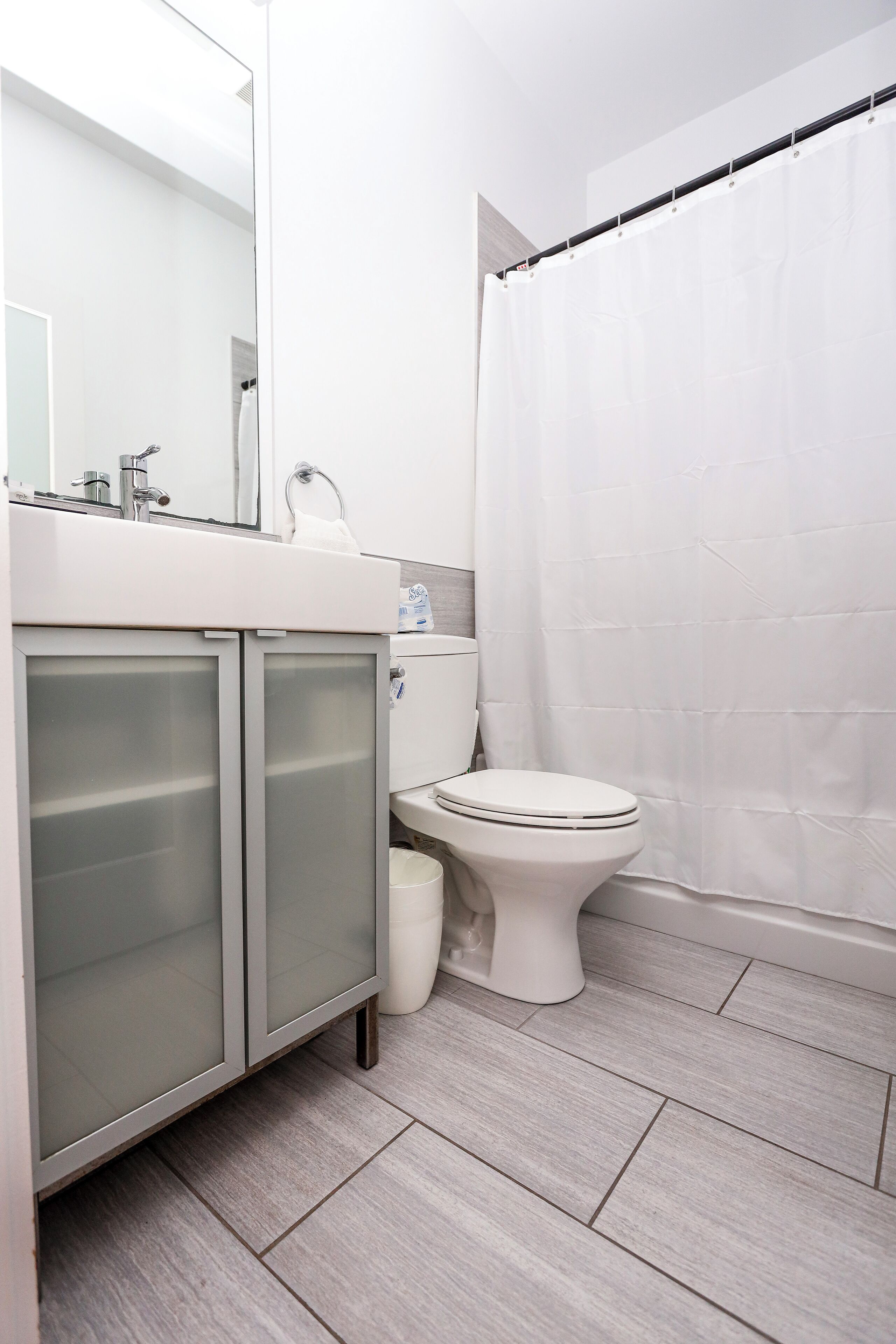 Ein modernes Badezimmer mit Waschbecken, Spiegel und Toilette in Weiß.