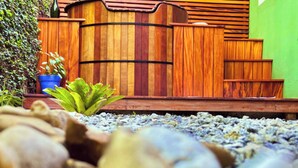 Una cerca de madera con parte superior curva y escalones que conducen a un muro verde.