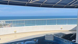 A hot tub on a balcony with a view of the ocean and a cityscape in the background. - Enjoy the terrace and the best sunset and view of the city. (Cartagena de Indias)