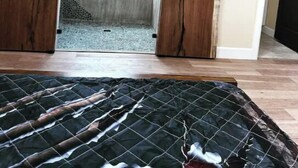 Een kamer met een schuifdeur van houten latten en een klein raam.