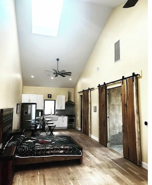 Relax in this serene space with a large bed, ceiling fan, and natural light pouring in through the skylight.