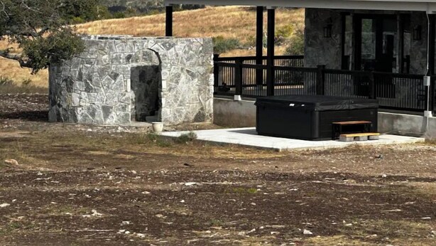 Een stenen constructie met een metalen dak, een stenen bank en een verhard gebied in een natuurlijke omgeving.