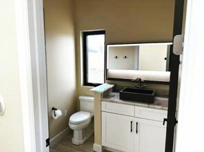 A compact bathroom with a toilet, sink, and mirror. - DarkSkies Hideaway an experience you will remember (Fredricksburg)