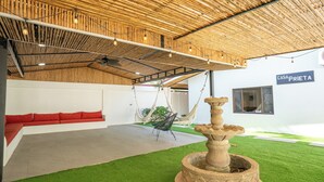 Un interior moderno con una silla colgante, una fuente de piedra y un sofá con cojines rojos.
