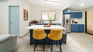 Una cocina moderna con una isla central, armarios azules y un refrigerador de acero inoxidable.