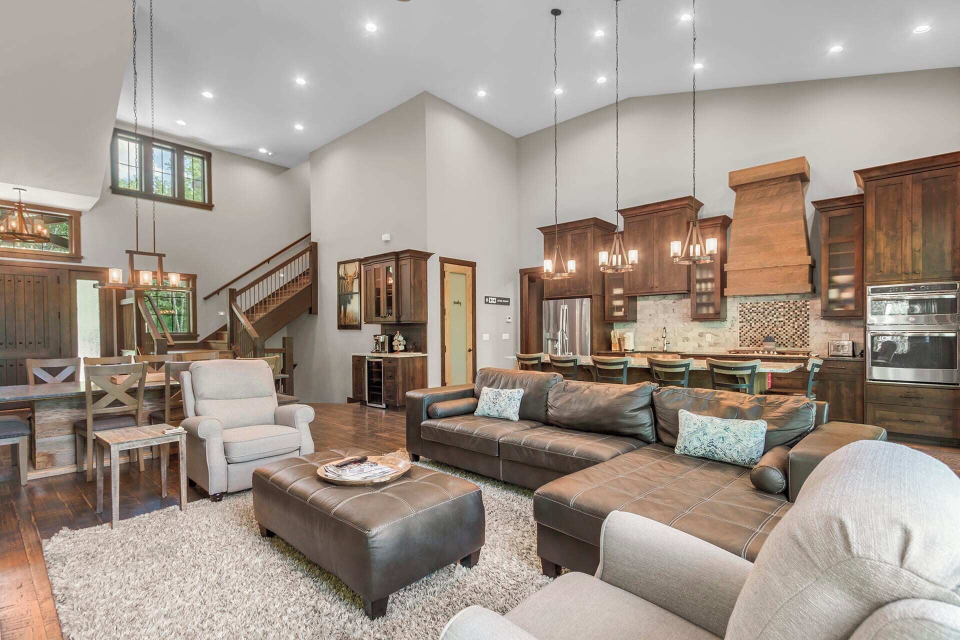 A spacious living room with a large sectional sofa, a dining area, and a kitchen with wooden cabinets and stainless steel appliances.