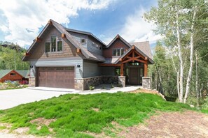 A two-story house with a garage, a stone foundation, and a large front yard.