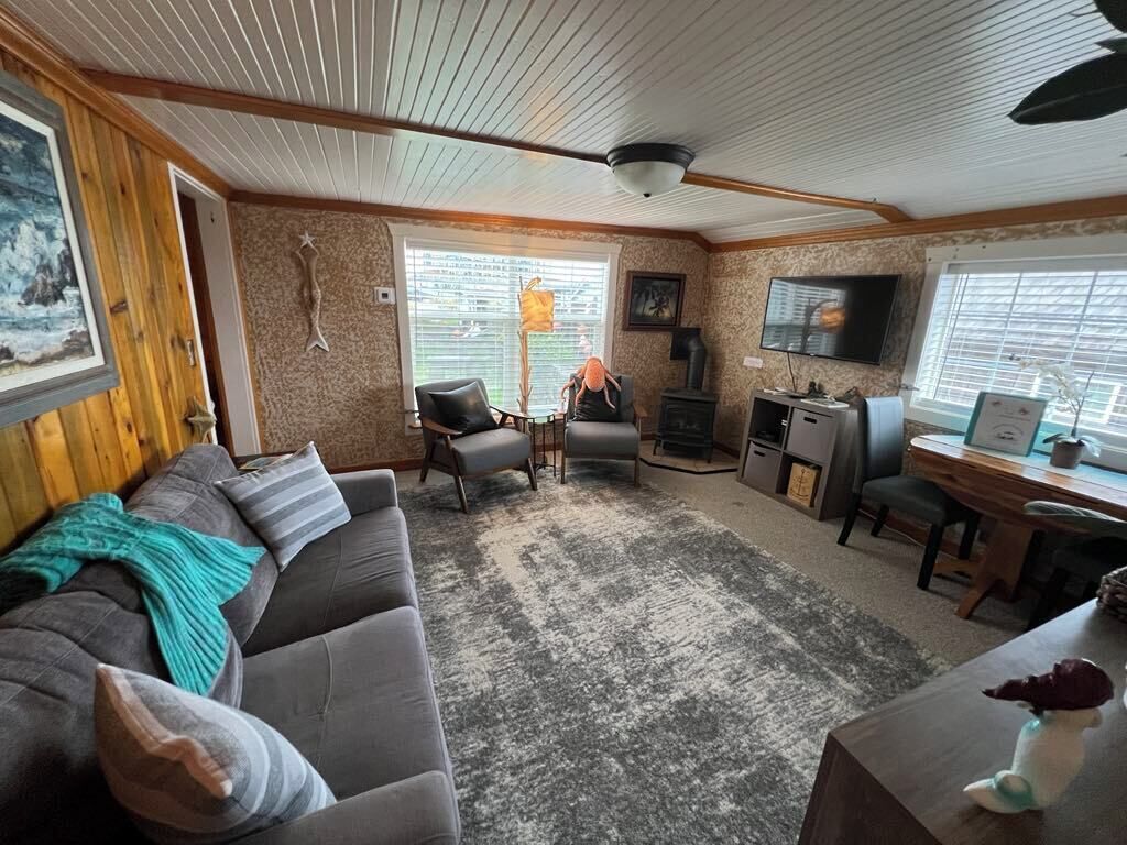 A cozy living room with a sofa, chairs, a fireplace, a television, and a desk.