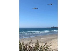 A beach with waves, a clear sky, and two birds flying. - Historic Beach Bungalow in Charming Nye Beach #6 (Newport)
