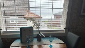 Uma mesa com duas taças de vinho e um suporte para menu, junto a uma janela com persianas.