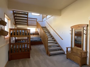 Cozy space with a central staircase and two bunk beds, a bench, and a mirror.