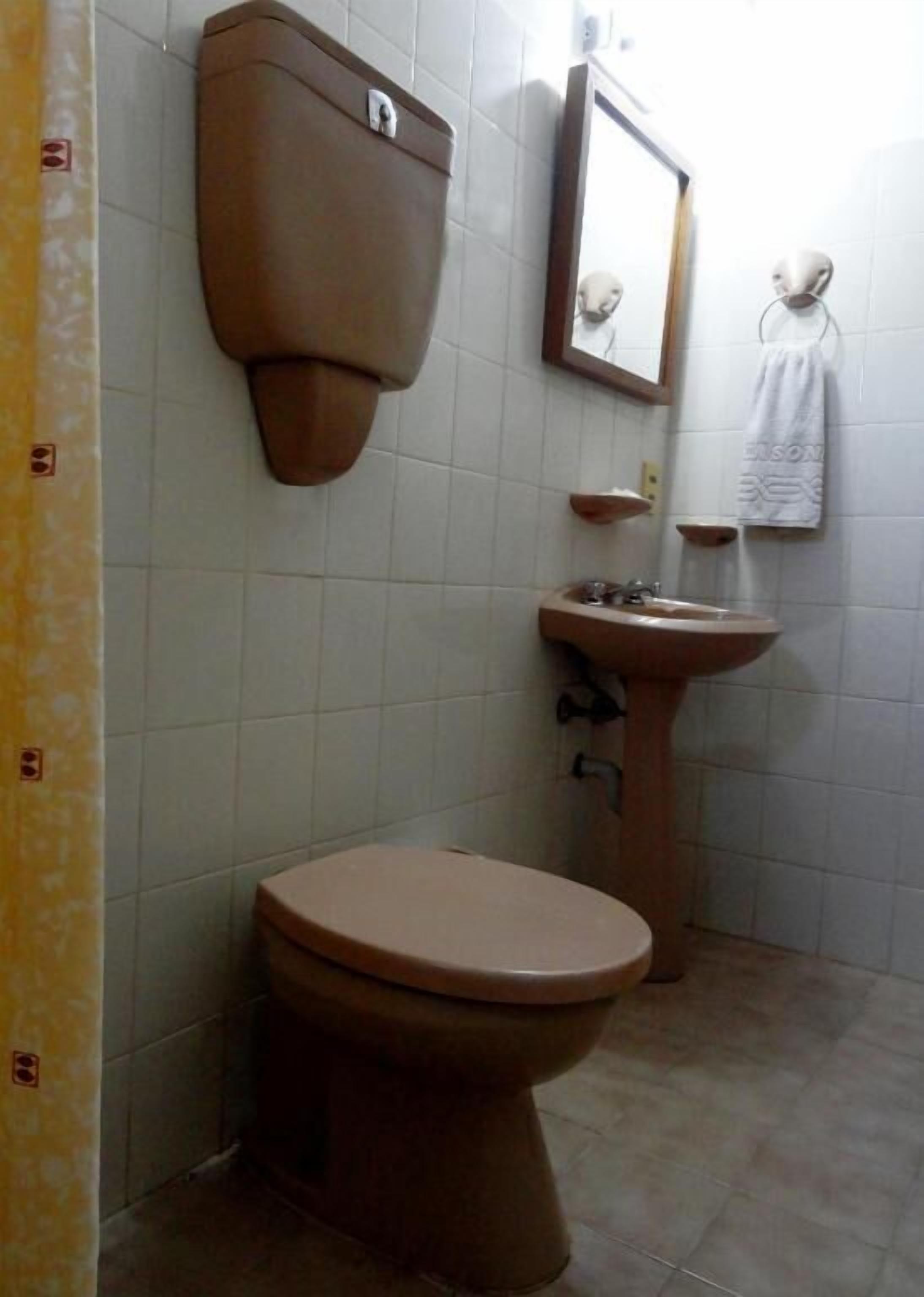 A bathroom with a toilet, sink, and mirror.