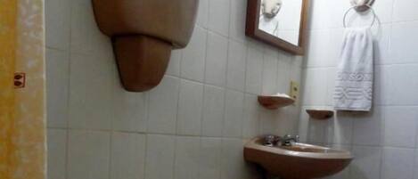 A bathroom with a toilet, sink, and mirror.