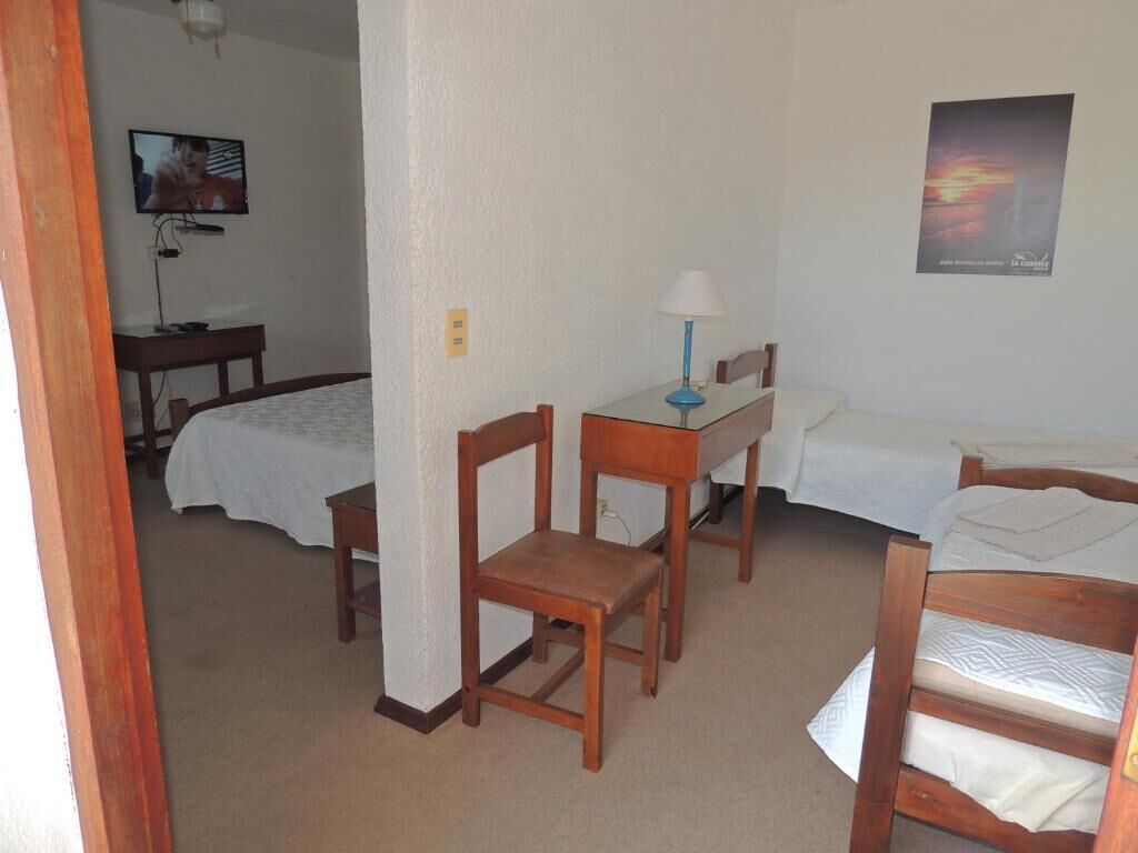 Una habitación con dos camas, un escritorio, una silla, un televisor y un cartel en la pared.