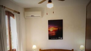 Una camera da letto con un letto di legno, due lampade sui comodini, una ventola a soffitto e un poster con un tramonto sulla parete.