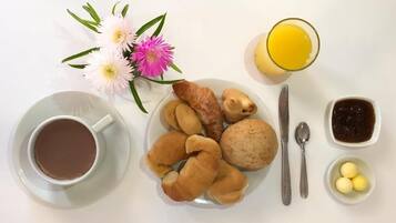 A breakfast setting with a plate of pastries, a cup of coffee, a glass of orange juice, and a small bowl of jam.