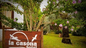 Segno di legno per l'Hotel La Casona con un disegno che raffigura un uccello e il sole.