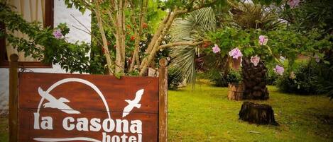 A wooden sign for La Casona Hotel with a bird and sun design.