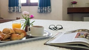 Un vassoio della colazione con croissant, una tazza di caffè e un bicchiere di succo d'arancia su un letto con una rivista.